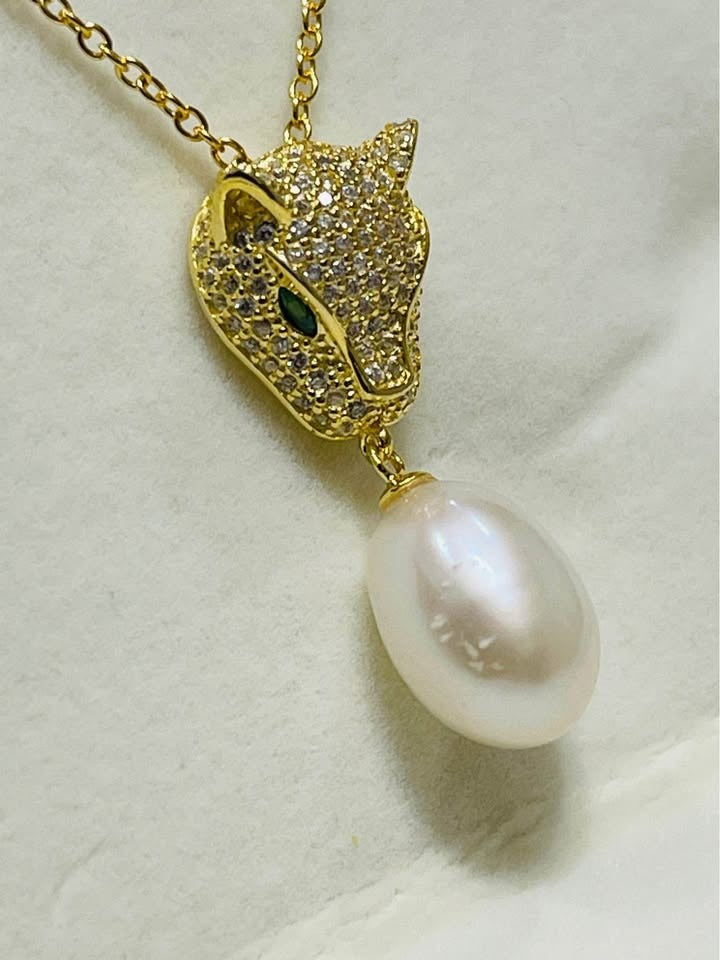 Detailed view of a gold panther pendant with emerald eyes, showcasing the South Sea pearl.