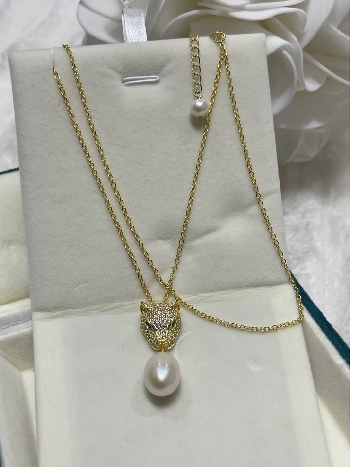 Gold panther necklace with emerald eyes and South Sea pearl, gracefully presented in its box.