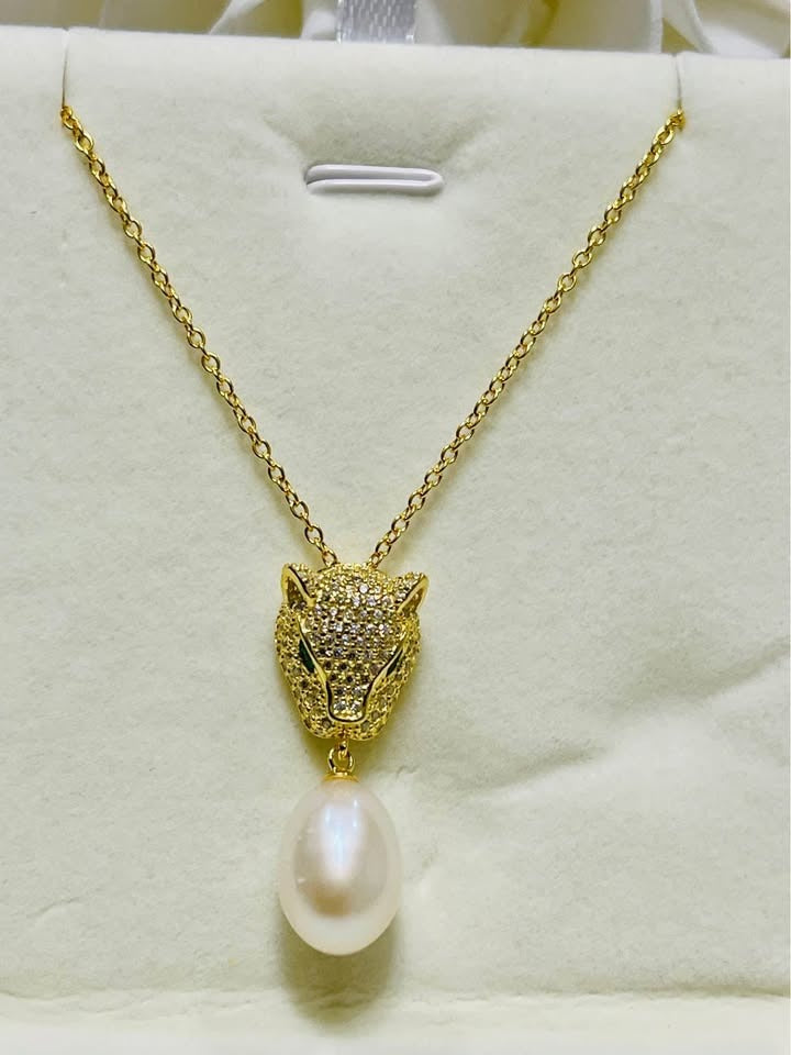 Gold panther head necklace with emerald eyes and a South Sea pearl, displayed on a white background.