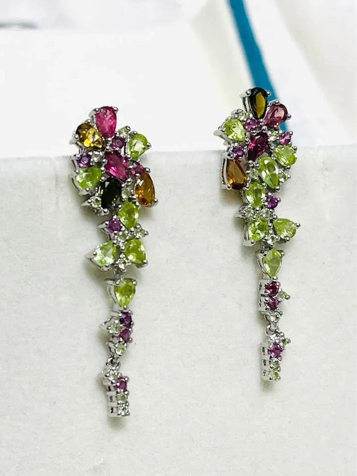Close-up of a pair of handmade gemstone earrings featuring peridot, rhodolite garnet, citrine, and sapphire.