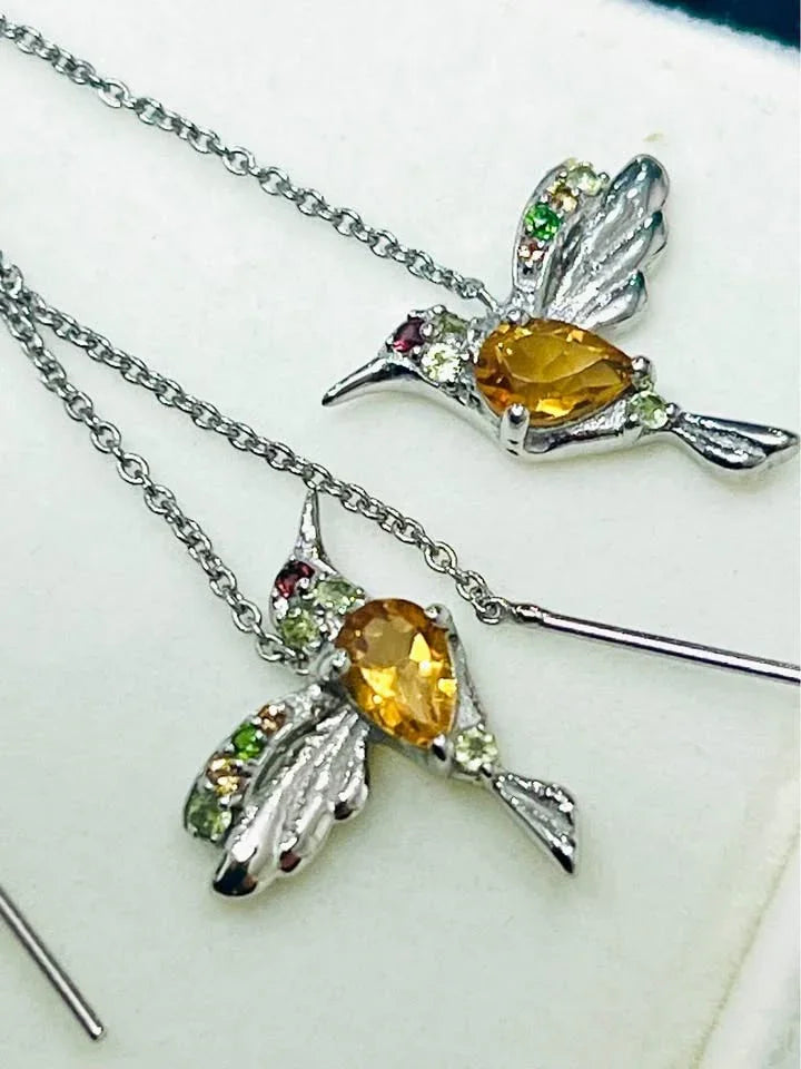 Close-up of the hummingbird design on the silver ear threader earrings, highlighting the gemstones.