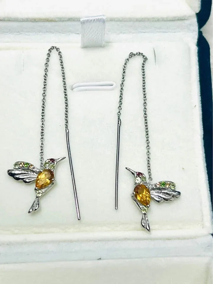 Elegant pair of hummingbird ear threader earrings with natural citrine and peridot stones, in a jewelry box.