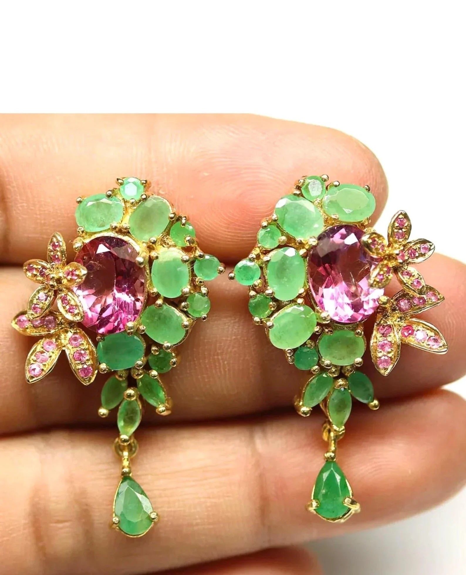 Close-up of Italian emerald and pink topaz earrings held in hand, highlighting their intricate gold-tone setting.