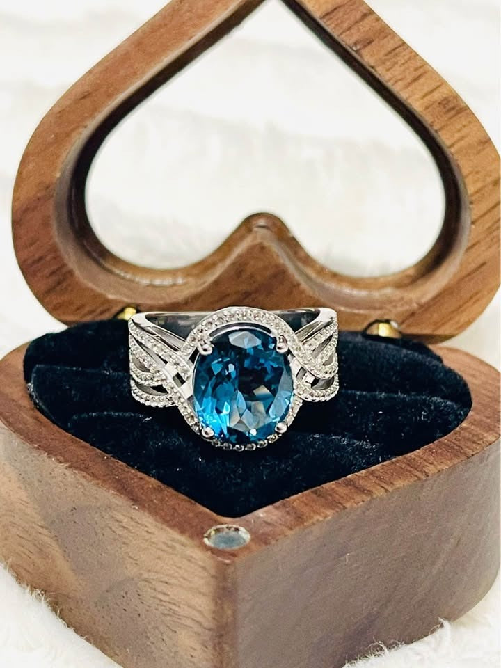 Angled view of a stunning London blue topaz and diamond ring, showcasing its sparkle and intricate setting.