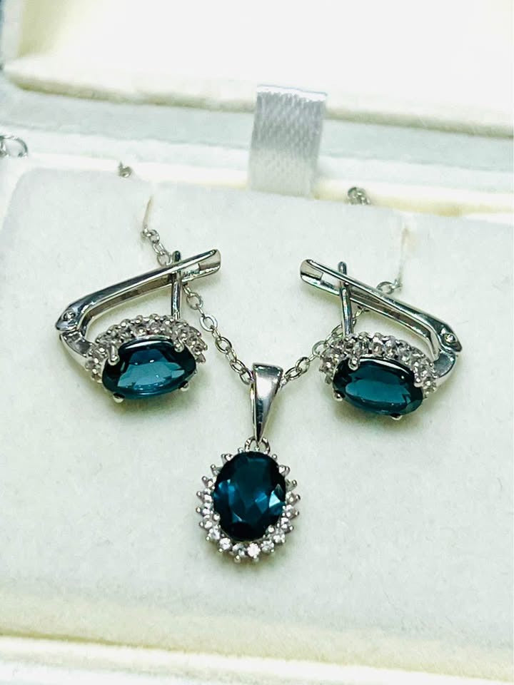 Natural London blue topaz earrings and pendant set on a clean white jewelry display.