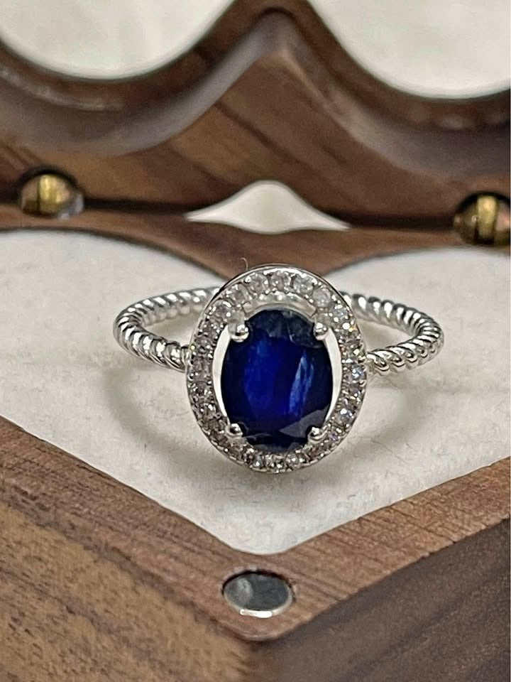 Macro view of a 2 carat natural sapphire ring with a sparkling diamond halo and elegant twisted rope band.