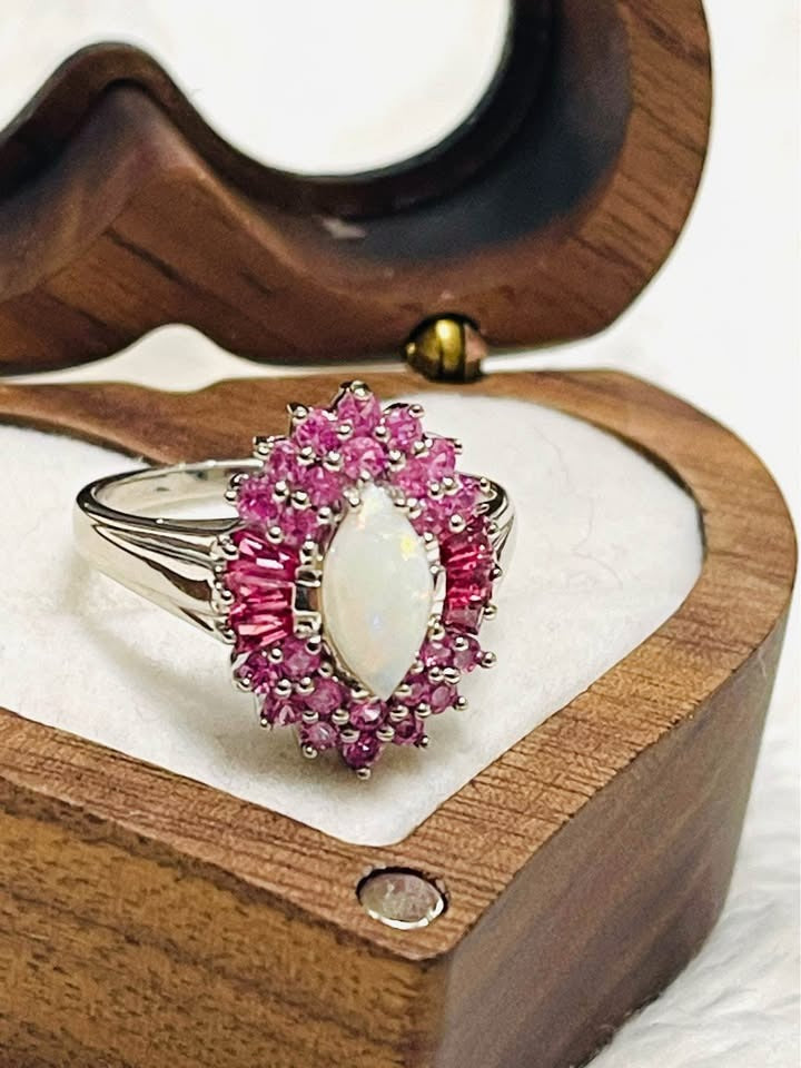 A beautiful ring with a marquise-cut Australian opal and pink sapphire halo, in a unique floral design.