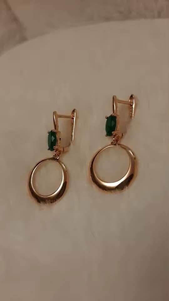 Modern 14k gold earrings with vibrant emeralds and a sleek, geometric open circle drop.