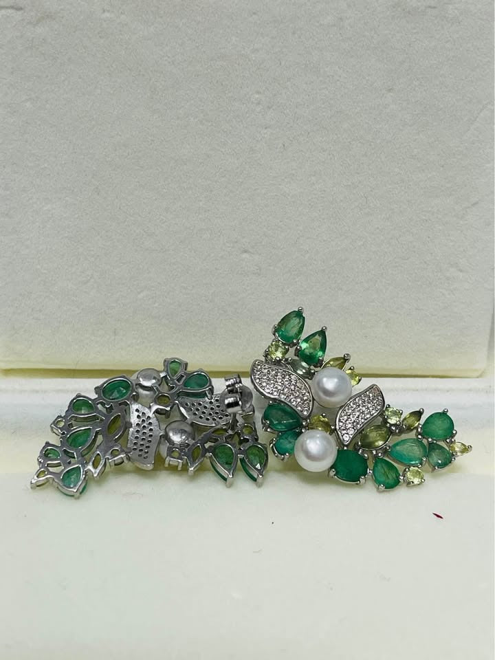 Detailed view of multi-gemstone earrings with Colombian emeralds, green sapphires, and white pearls.