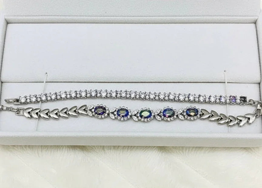 Angled view of two sterling silver bracelets with colorful mystic topaz, showcased within a velvet-lined box.