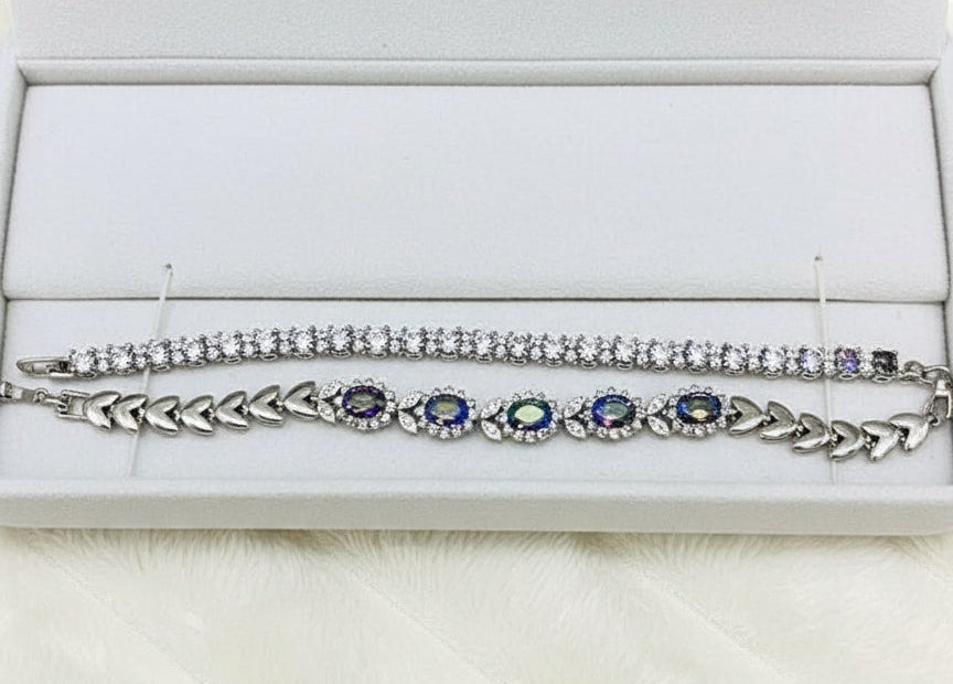 Angled view of two sterling silver bracelets with colorful mystic topaz, showcased within a velvet-lined box.