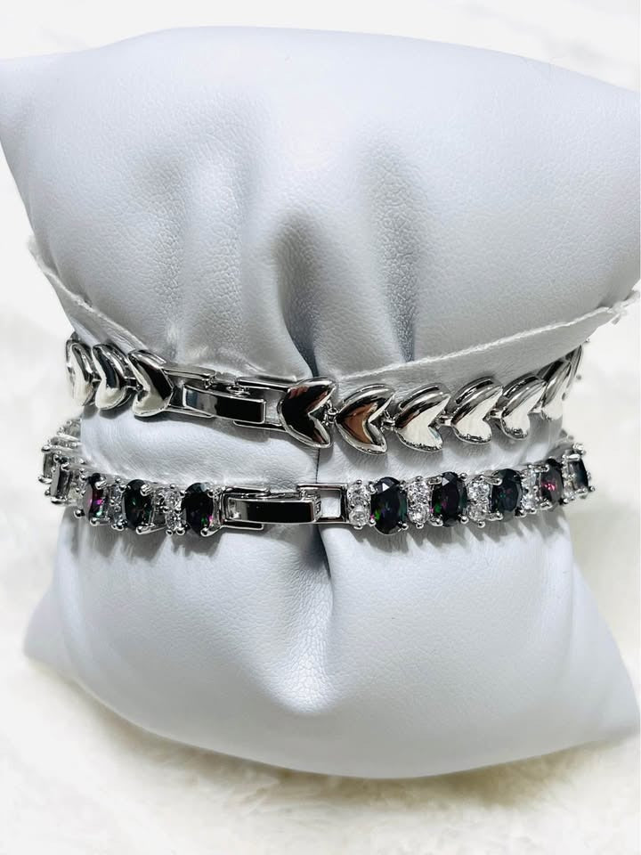 Close-up of the clasps on two sterling silver mystic topaz bracelets, highlighting the heart and box closures.