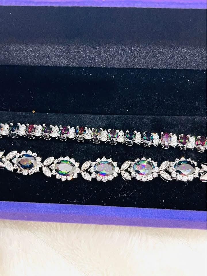 Top view of two sterling silver bracelets featuring vibrant mystic topaz stones in a purple display box.