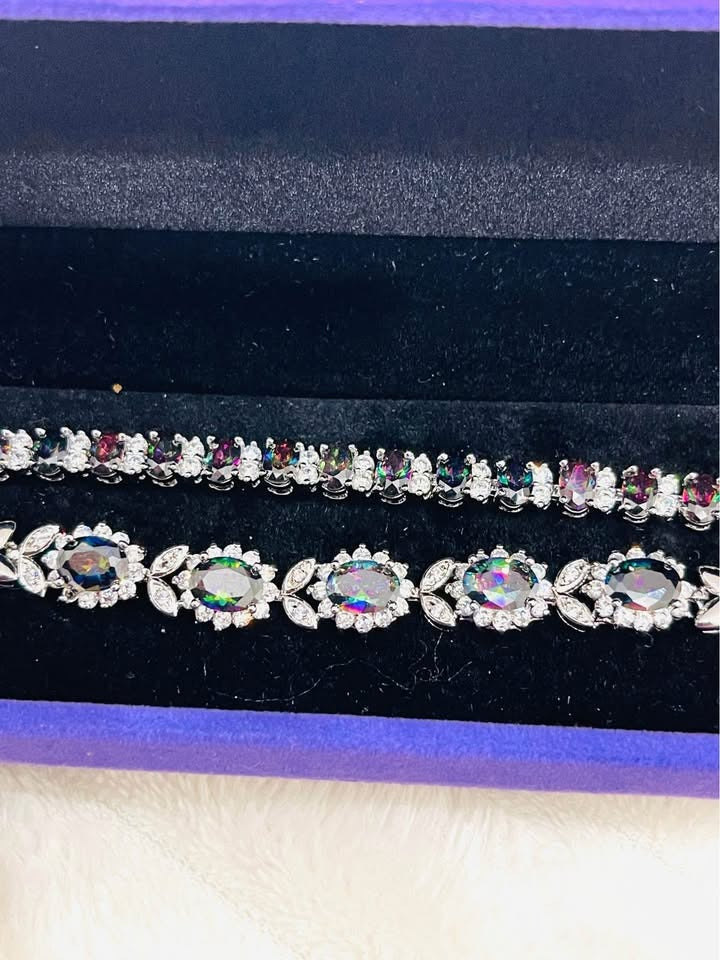 Top view of two sterling silver bracelets featuring vibrant mystic topaz stones in a purple display box.