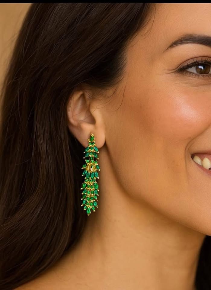 A woman modeling fancy natural Colombian emerald earrings, highlighting the jewelry's elegant drop and length.