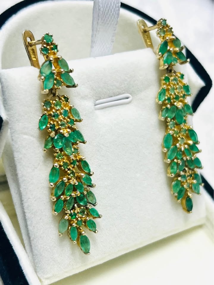 Elegant pair of natural Colombian emerald earrings arranged in a black and white jewelry display box.