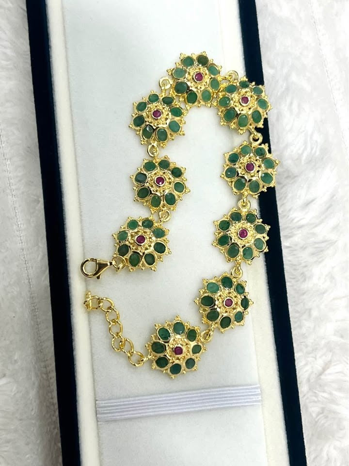 Exquisite floral bracelet with natural Colombian emeralds, rubies, and gold. Detailed clasp and chain shown.