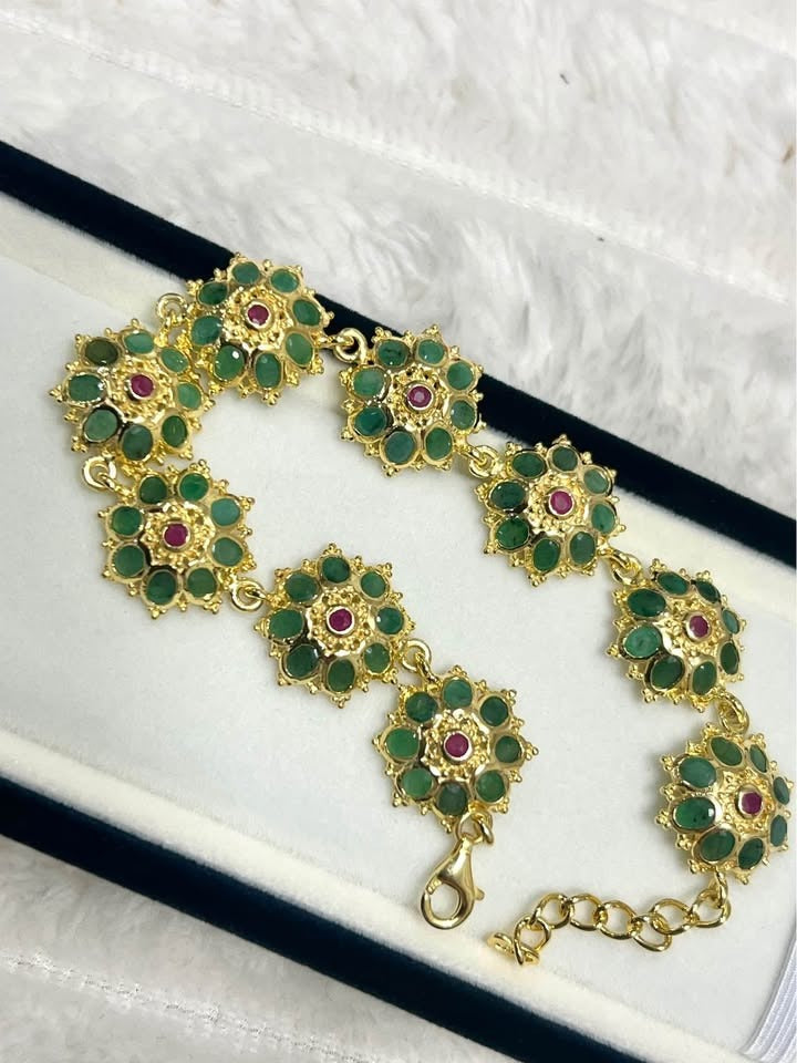  Elegant floral bracelet with natural Colombian emerald and ruby gemstones on a white background.