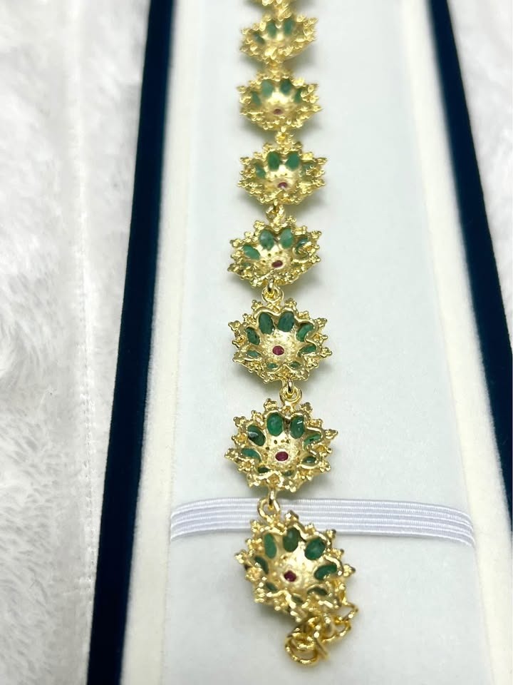 Close-up of the bracelet's floral links and elegant clasp. Features vibrant emeralds and rubies.