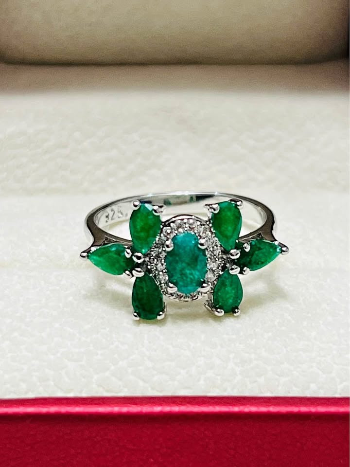 Beautiful natural emerald flower ring in sterling silver, featuring an oval center stone surrounded by marquise emeralds.