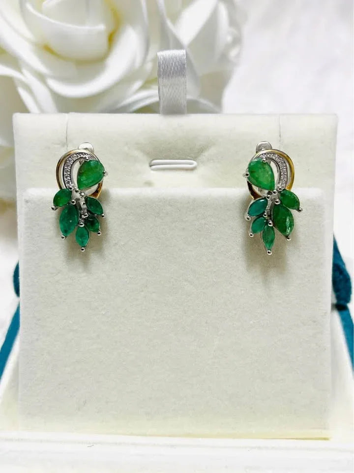 Natural sterling silver and gold earrings with emeralds, presented on a white display.