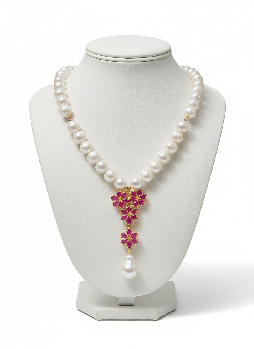 Stunning natural freshwater pearl necklace featuring a floral ruby and baroque pearl drop on black.