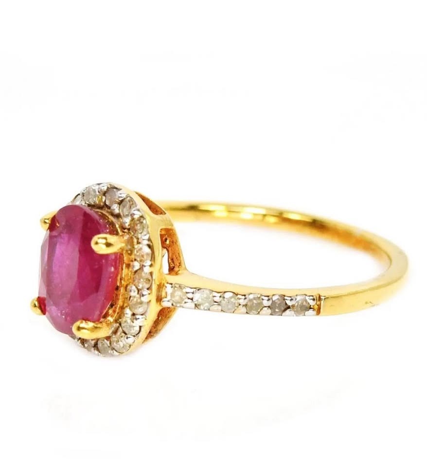 Close-up side view of a natural ruby and natural diamond halo ring on a white surface.