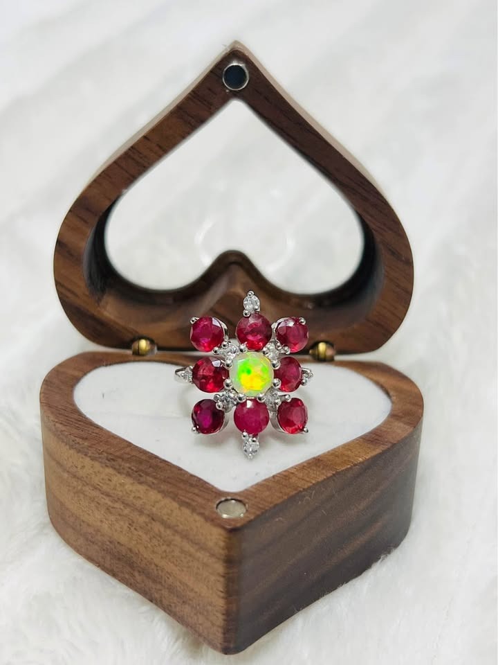  A stunning ring featuring a central fire opal with a floral-inspired halo of natural rubies and white stones.