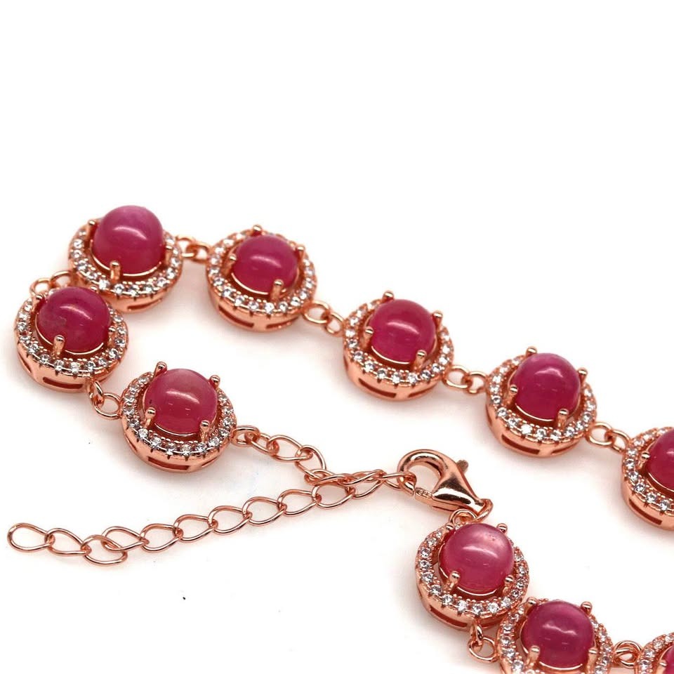 Rose gold bracelet with natural rubies and diamond halos, featuring a detailed clasp.