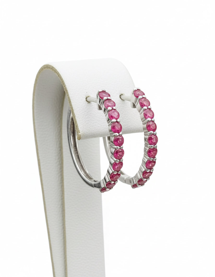 Natural ruby sterling silver hoop earrings hanging on a branch, highlighting the vibrant color.