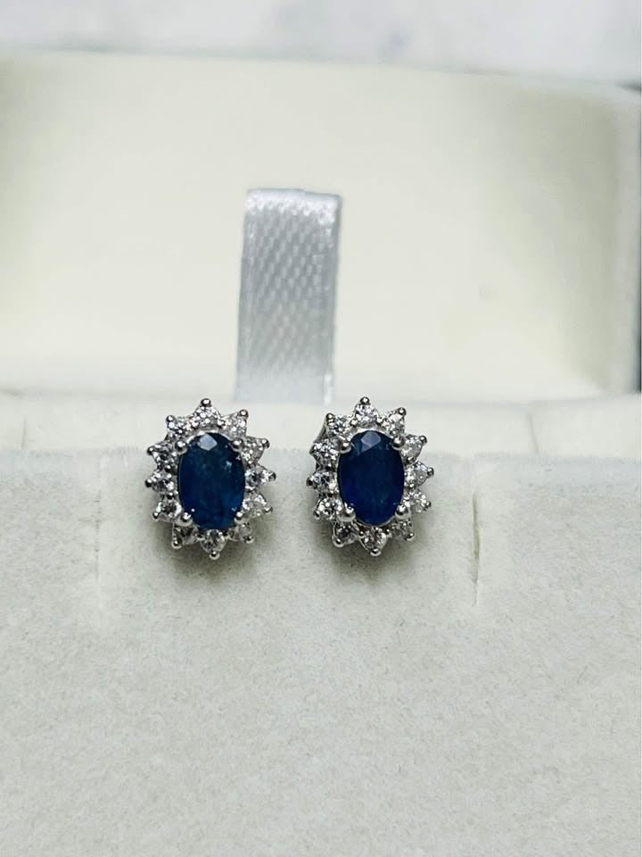 Exquisite natural sapphire oval-cut stud earrings with sparkling diamond halo in white gold.