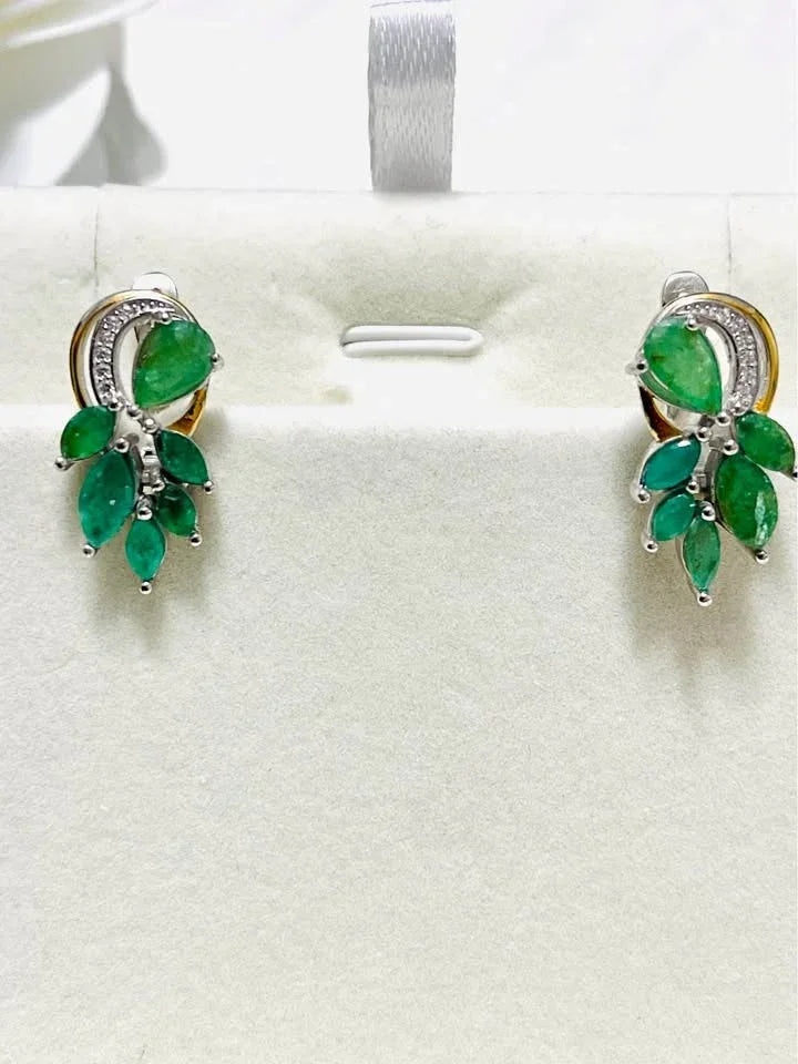 A front-on view of natural sterling silver emerald earrings with two-toned gold and silver.
