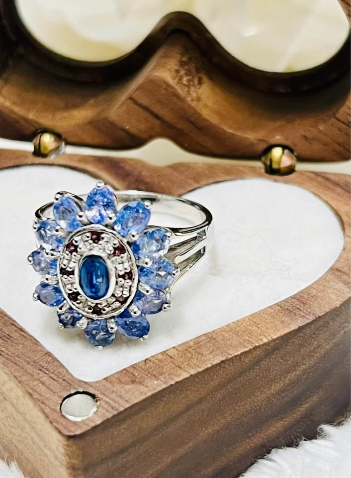 Natural sterling silver tanzanite ring with a flower design, displayed in an open heart-shaped wooden box.