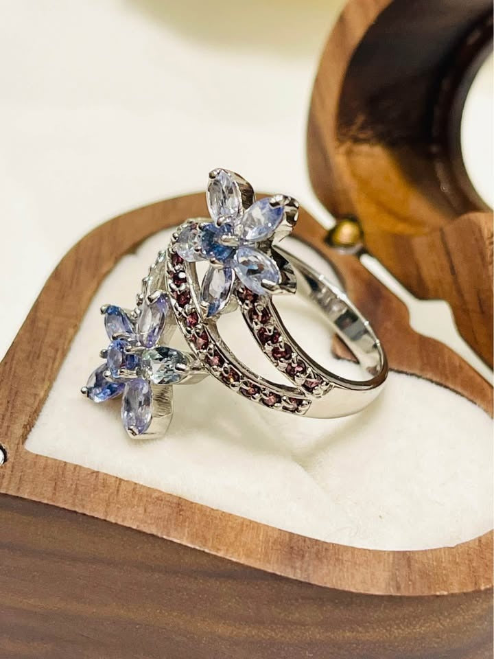 Detailed shot of a sterling silver ring with natural tanzanite and rhodolite gems, highlighting the intricate design.