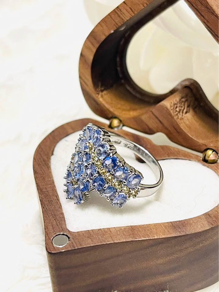 A side-view of a natural tanzanite and sapphire ring, highlighting the elegant profile of the sterling silver band.