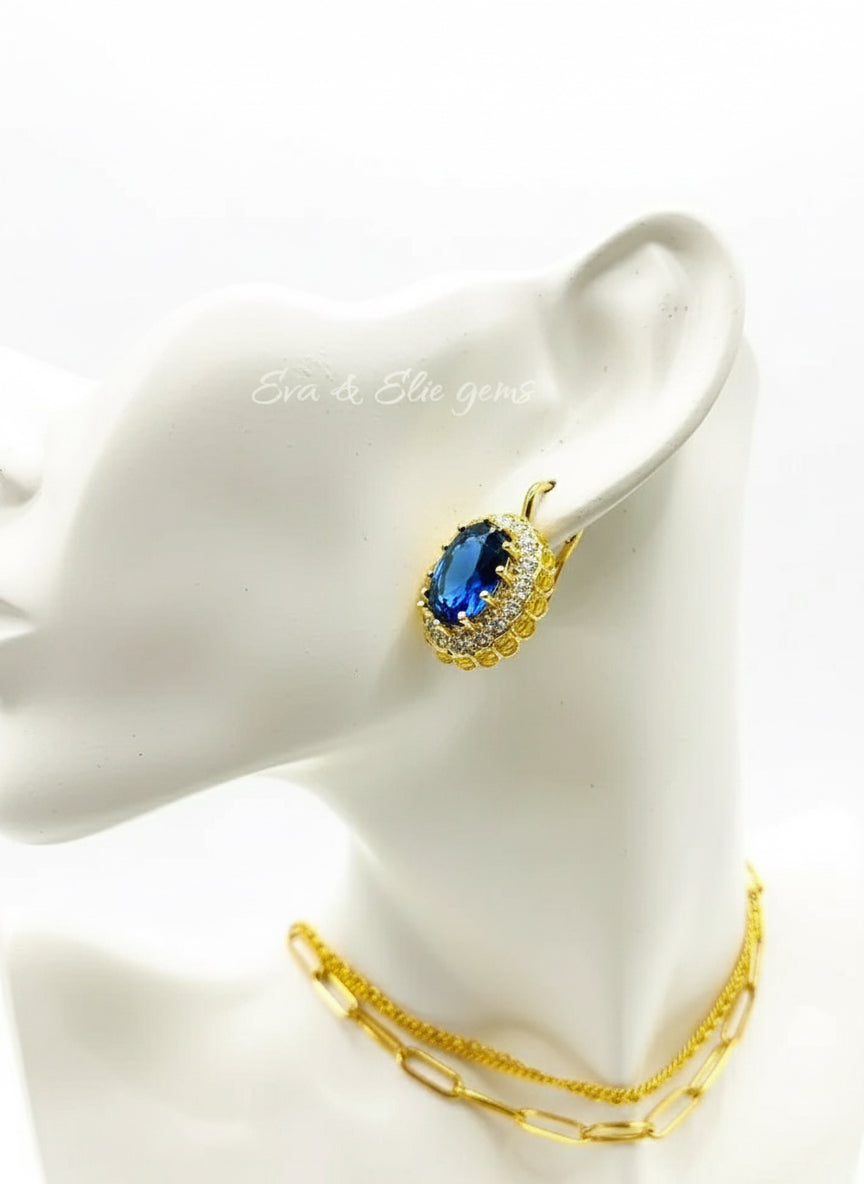 Close-up of a blue sapphire earring on a model's ear, showcasing the 18k gold vermeil and halo details.