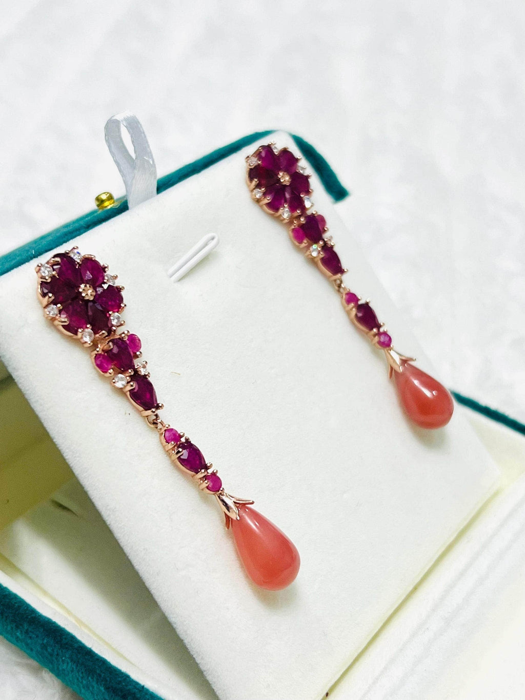 Angled view of exquisite prehnite and ruby dangle earrings, showcasing their vibrant gemstones and unique design.