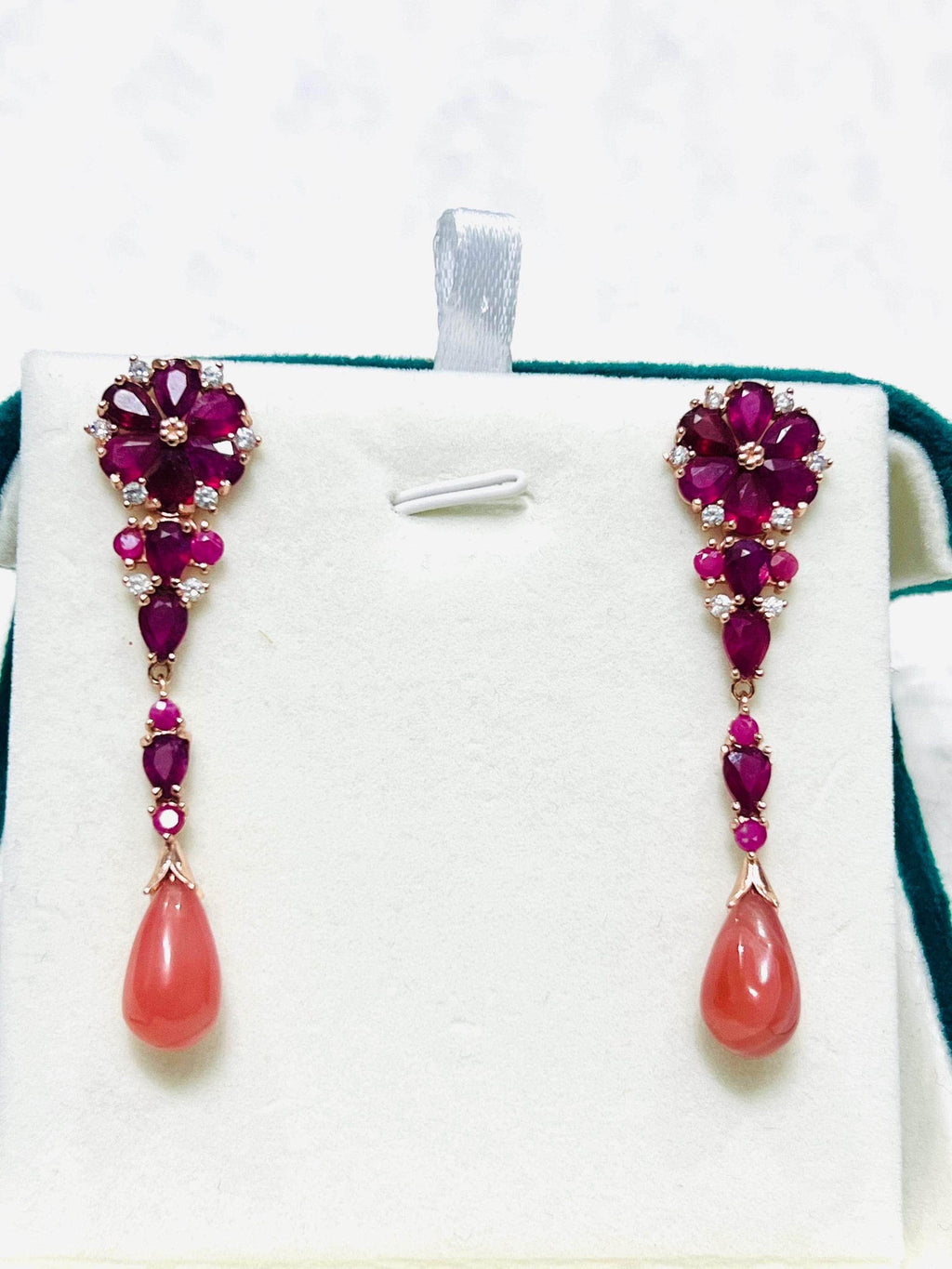 Pair of elegant dangle earrings with red rubies, sparkling accents, and teardrop prehnite, displayed straight.