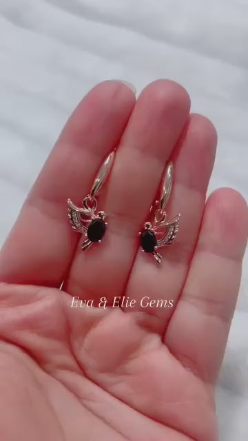 Close-up of a person wearing a 14K gold-filled onyx dove earring, showcasing its size and dangle.