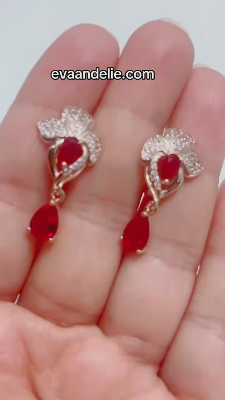 Elegant rose gold-toned earrings with vibrant red gemstones and intricate design.