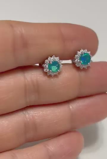 A pair of blue fire opal stud earrings with a sparkling halo design.