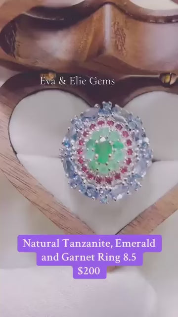 A stunning ring with natural tanzanite, emerald, and garnet gemstones in a colorful design.