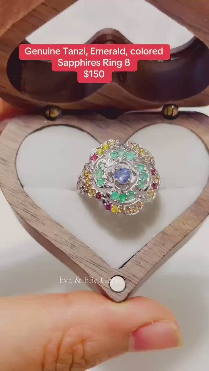 This genuine tanzanite, emerald, and sapphire ring features a stunning floral design.