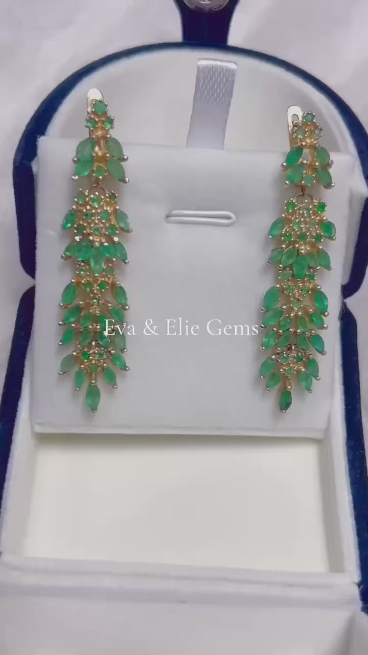 A pair of long, fancy dangle earrings featuring a beautiful cascade of genuine Colombian emeralds.