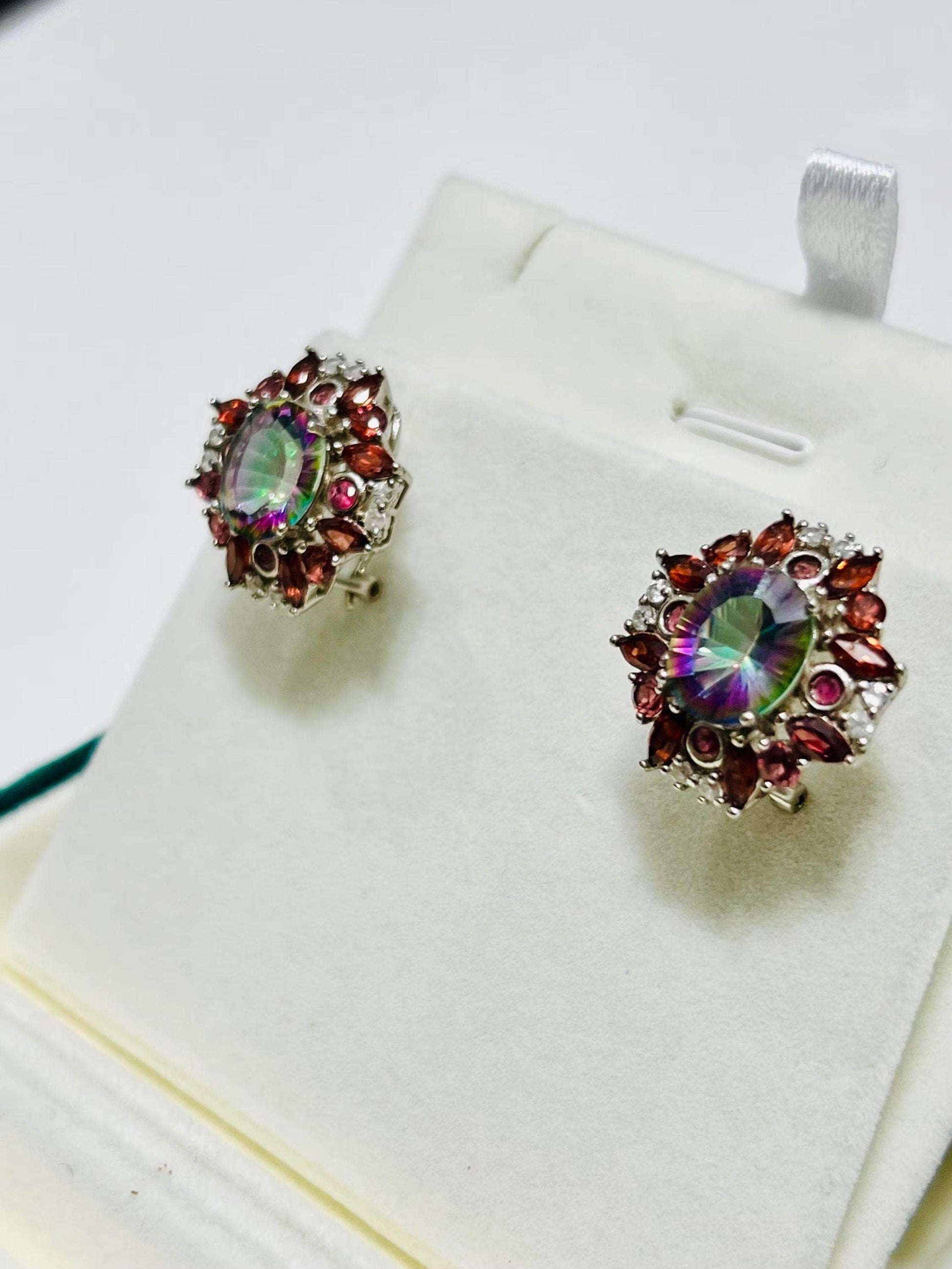 Side view of dazzling rainbow quartz and garnet omega-back earrings on a white display. Elegant gemstone jewelry.