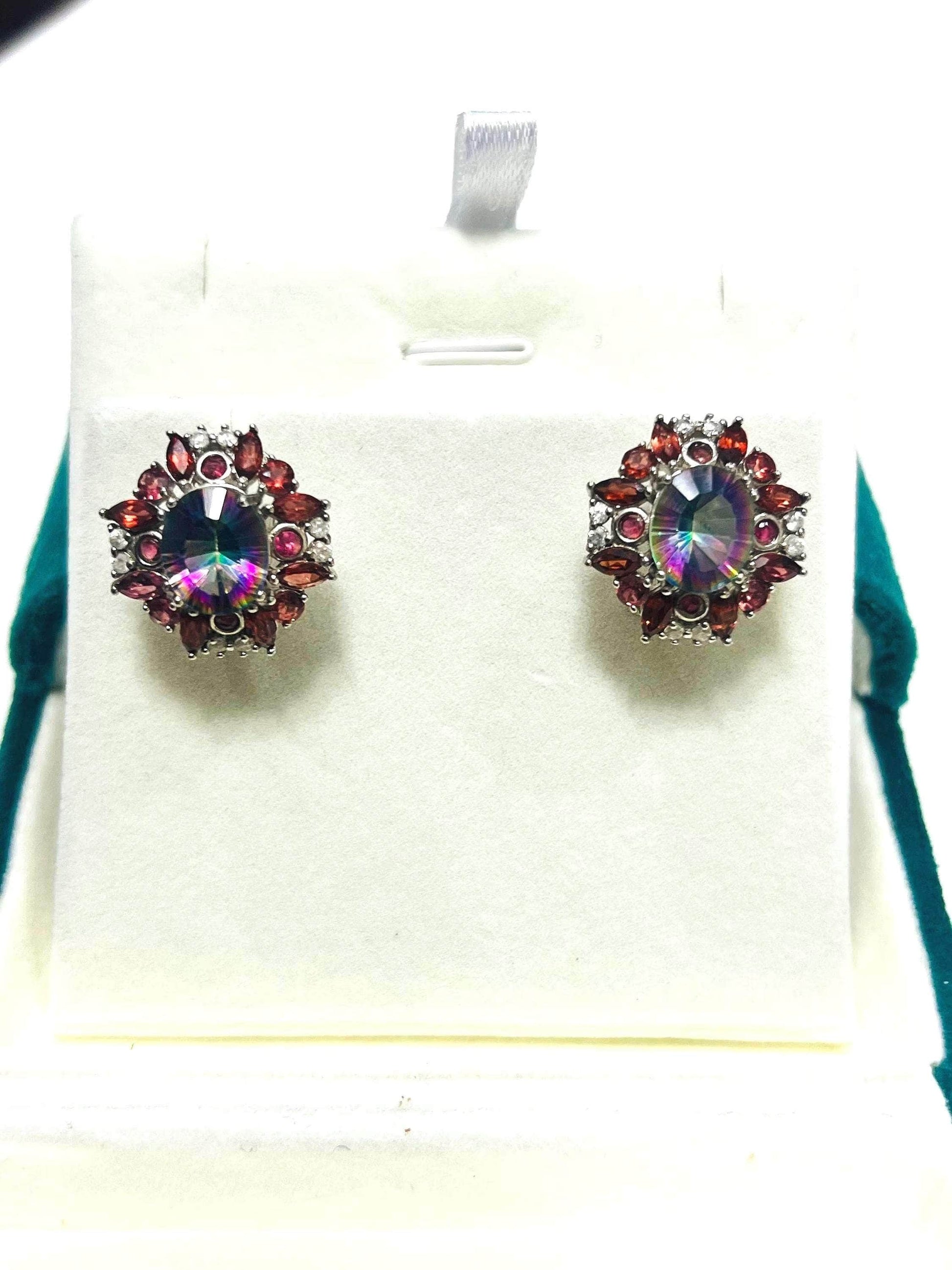 Pair of striking rainbow quartz and garnet omega-back earrings displayed on a white jewelry stand. Front view.