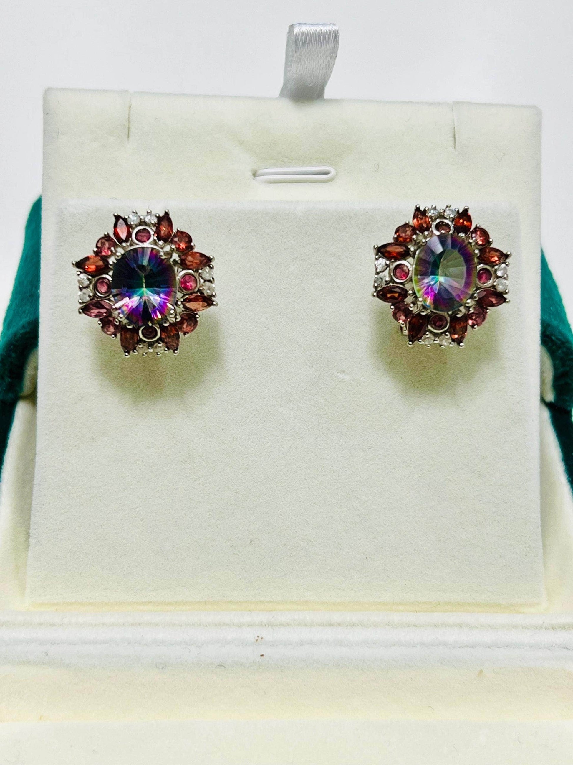 Full frontal view of brilliant rainbow quartz and garnet omega-back earrings in a jewelry box setting.