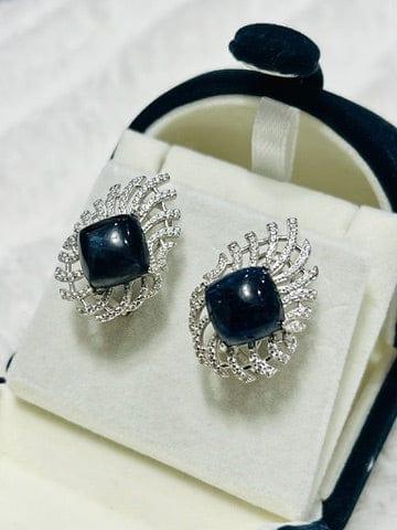 Diagonal glance at raw blue sapphire earrings, highlighting the contrast between the rough sapphire and polished setting.