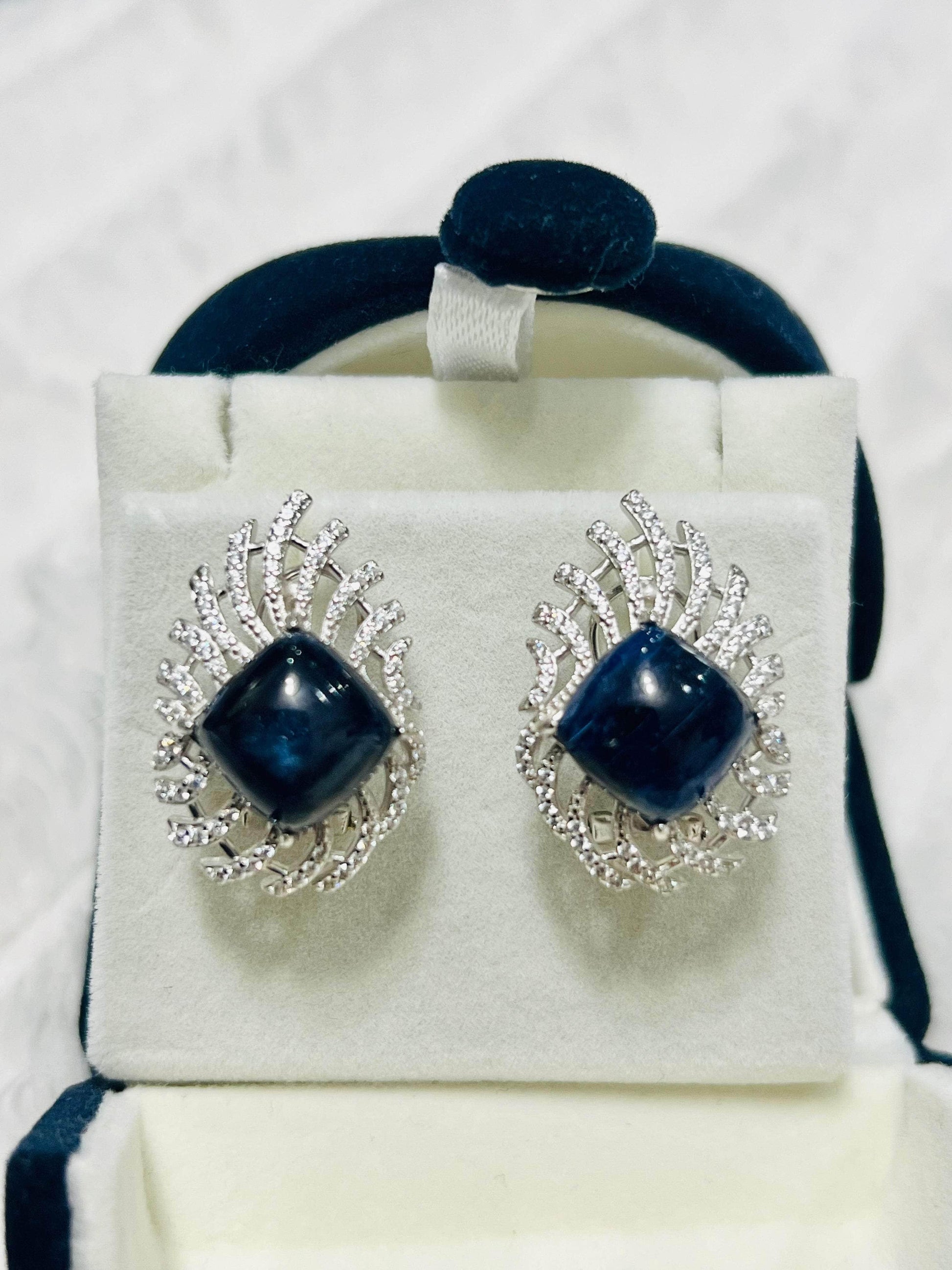 Raw blue sapphires encircled by sparkling white stones, presented in a box.