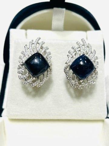 Top-down view of raw blue sapphire earrings featuring a unique cushion cut surrounded by sparkling white stones.